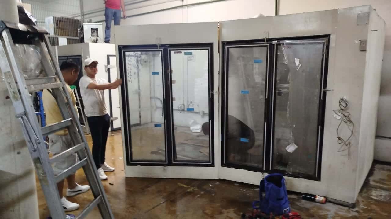 Personal de recolección desmontando una cámara de refrigeración comercial en una bodega